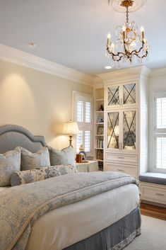 a bedroom with a large bed and a chandelier in front of the window