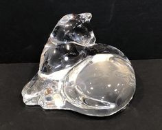 a glass figurine sitting on top of a black table next to a wall