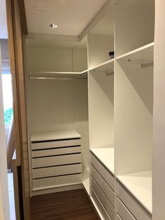 an empty walk in closet with white shelves and drawers