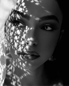 black and white photograph of a woman's face with the shadow of a tree behind her