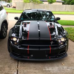 a black car with red stripes parked next to a white car