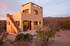 a house in the desert with stairs leading up to it's second floor and two levels