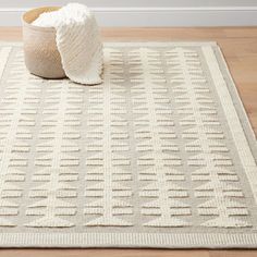 a white rug on the floor with a basket next to it