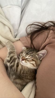 a woman is laying in bed with her cat