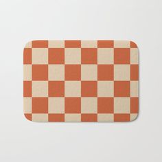 an orange and white checkerboard pattern bath mat on a white background with room for text