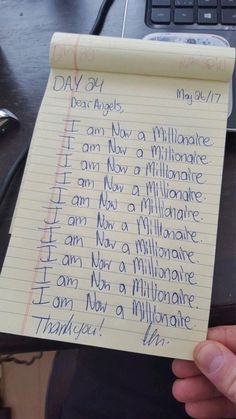 someone is holding up a piece of paper with writing on it that says i am now a millionaire