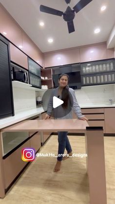 a woman standing at a kitchen counter in front of a ceiling fan with lights on