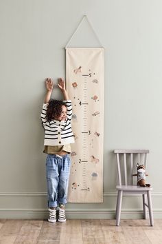 a little boy standing in front of a growth chart with his hands on the wall