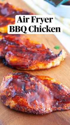 two pieces of chicken sitting on top of a wooden cutting board with bbq sauce