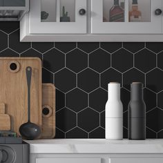 a kitchen counter with cutting board, utensils and bottles on it