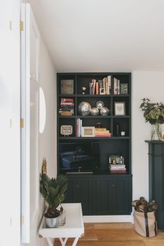 a living room filled with furniture and a book shelf next to a fire place on top of a hard wood floor