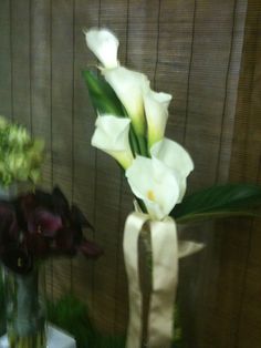 two vases with flowers in them sitting on a table next to a wooden wall