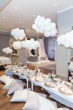 a table set up for a party with white balloons