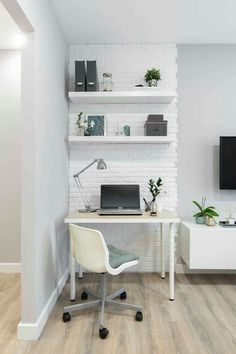 a white desk with a laptop on it in front of a brick wall and shelves