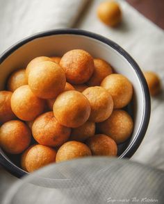 a bowl filled with oranges sitting on top of a white cloth covered tablecloth