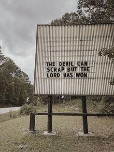 a sign that has been placed on the side of a road in front of some trees