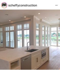 an empty kitchen with lots of windows and white counter tops in front of sliding glass doors