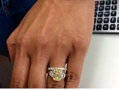 a woman's hand with a yellow diamond ring