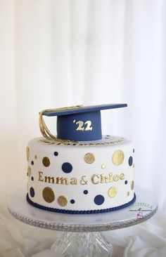 a white cake with gold polka dots and a blue graduation cap on top that reads 22