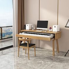 a computer desk with a keyboard and monitor on it in front of a large window