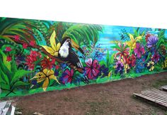 a colorful mural painted on the side of a building with flowers and toucans