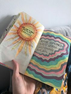 someone is holding up a book with an image of the sun on it in their hand