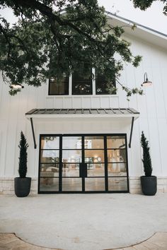 a white building with large windows and black planters on the front entrance to it