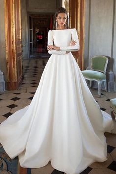 a woman wearing a white wedding dress standing in front of a doorway with her hands on her hips