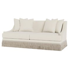 a white couch with pillows on it and fringe trimming around the armrests