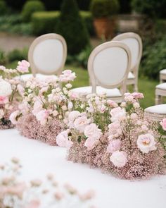 rows of white chairs with pink flowers in them on an outdoor wedding venue table setting