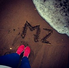 someone's feet in the sand next to an arrow drawn in the sand at the beach