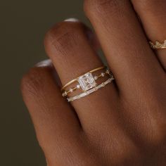 a woman's hand with two gold rings on her left and one diamond ring on the right