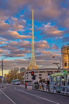 people are standing on the side of the road in front of a tall tower that is lit up