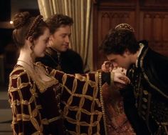 the tudors are talking to each other in their regal dress and eating food together