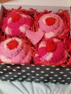 a box filled with pink and red heart - shaped stuffed animals sitting on top of a polka dot blanket