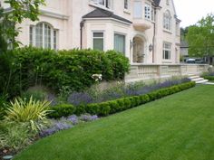 a large house with many bushes and flowers in the front yard