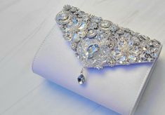 Beautiful brooch bridal clutch  This purse can be worn as a clutch or attach the chain strap to hang off your shoulder.  It shines and sparkles and will go wonderfully with your wedding attire.  Also a beautiful accessory for your bridal shower, rehearsal dinner, Bach party and more.  Color :White  Silver Chain Strap included : Yes Approx 8 inches width and 4 inches tall Brooch detail design on flap. Snap closure Crystal Clutch Evening Bag For Wedding, Crystal Evening Bag For Wedding, Bling Clutch Evening Bag For Wedding, Silver Rhinestone Bridal Accessories For Evening, Silver Crystal Bridal Accessories For Evening, Wedding Crystal Clutch Evening Bag, Glamorous White Evening Bag For Wedding, Elegant Silver Bridal Accessories For Evening, Luxury Wedding Clutch With Bling