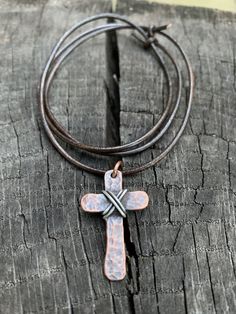 "Show your faith with this humble, rustic cross. I hammer and forge each of these crosses by hand from pure, organic copper and wrap it with 925 Sterling silver. Each cross is finished with a rustic patina which gives it an antiqued look. These are perfect for men or women. Dark brown cowhide leather cording is 24\" in length and is adjustable. Necklace slips over the head. If you would like another style chain like a ball chain or cable chain please message me before ordering. Prices may vary b Handmade Adjustable Cross Necklace, Artisan Adjustable Cross Jewelry, Rustic Brown Hammered Jewelry, Rustic Cross Jewelry For Gifts, Handmade Adjustable Crucifix Cross Necklace, Hand Forged Silver Cross Pendant Jewelry, Sterling Silver Hand Forged Cross Pendant Necklace, Oxidized Finish Cross Necklace For Gifts, Rustic Cross Jewelry Gift