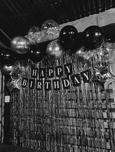 black and white photograph of balloons, streamers and happy birthday sign hanging from the ceiling