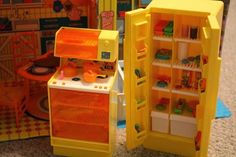 two toy refrigerators sitting next to each other on the floor in front of a play kitchen