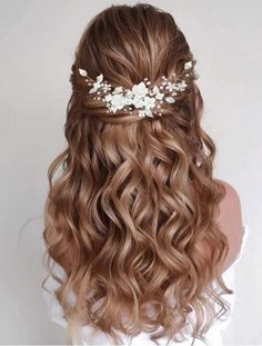 the back of a woman's head with long wavy hair and flowers in her hair