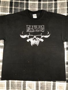 Danzig - Vintage - Classic Hardcore Metal Punk Rock Band T Shirt - Size XXL The shirt shows wear and fading. There are some bleach marks on the front of the shirt. There are holes in the armpits and one sleeve. The graphic shows cracking and fading. Please refer to the photos Punk Black T-shirt For Biker Events, Distressed Rock T-shirt For Streetwear, Alternative Graffiti Print Tops For Concerts, Alternative Style Graffiti Print Top For Concerts, Grunge Cotton Tops For Biker Events, Band Merch Skull Print Shirt For Streetwear, Band Merch Shirt With Skull Print For Streetwear, Rocker Distressed T-shirt For Concert, Band Merch Tops For Concert With Skull Print