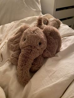 an elephant stuffed animal laying on top of a bed