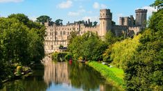 an old castle sits on the edge of a body of water with trees around it