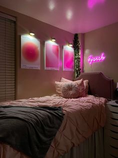 a bedroom with pink and black decor on the walls, two pictures above the bed