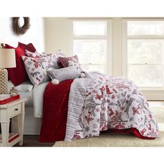 a bed with red and white comforters in a bedroom next to a window,