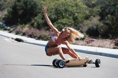 a woman riding a skateboard down the side of a road