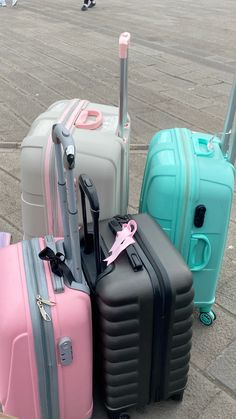 three suitcases are sitting on the ground with one pink and one blue, all in different colors