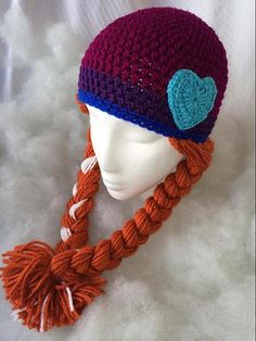 a crocheted hat with a heart on the top and braids at the bottom