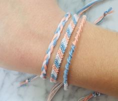 two bracelets on someone's arm, one is blue and the other is pink